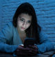 Dramatic portrait of sad scared young woman on smart mobile phone suffering cyber bullying and harassment. feeling lonely, depressed and in fear being online abused by stalker. In dangers of internet.