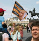 A pro-Kremlin activist holds a flag with an image of Russian President Vladimir Putting and the words in Russian 'For the Motherland, for the sovereignty, for the Putin', near the Kremlin in Moscow, Russia, Sunday, June 25, 2023. Troops deployed in Moscow the previous day to protect the capital from Wagner mercenaries withdrew from the capital, and people swarmed the streets and flocked to cafes. (AP Photo/Dmitri Lovetsky)