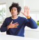 Young african american man wearing casual sweater sitting at home Swearing with hand on chest and open palm, making a loyalty promise oath