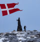 Un hombre camina mientras la bandera danesa ondea junto a la estatua de Hans Egede antes de las elecciones generales del 11 de marzo en Nuuk, Groenlandia