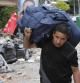 Un hombre carga una maleta en Lorca frente a cascotes de un derrumbe provocado por el terremoto.