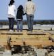 Una familia contempla el océano Pacífico desde el lugar donde se levantaba su casa, arrasada por el tsunami del pasado 24 de abril.