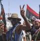 Rebeldes libios hacen la señal de la victoria a las puertas de la ciudad de Brega