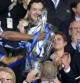 El jugador del Chelsea, Didier Drogba, le entrega la copa al propietario del club, Roman Abramovic