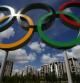 Los cinco aros olímpicos y, al fondo, algunos de los edificios donde se alojan los atletas