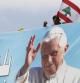 Un hombre coloca una bandera libanesa sobre una gran imagen del Papa en Beirut