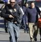 Padres se alejan del área del tiroteo de Connecticut protegidos por agentes armados.