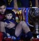 Lionel Messi sostiene a su hijo al lado de la Copa de campeones de Liga