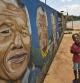Un niño pasea ante un dibujo de la cara de 'Madiba' en Soweto