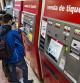 Pasajeros de TMB comprando billetes de transporte público en las máquinas expendedoras del metro de Barcelona