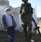 Un niño mira a un hombre vestido de soldado en la frontera con Ucrania