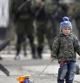 Un niño pasea un coche de juguete delante de soldados prorusos en la zona exterior de la base militar ucraniana en Perevalne, Crimea