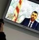 Un informador gráfico fotografía un monitor en la sala de prensa de la Audiencia Nacional durante la declaración por videoconferencia del conseller de Territorio, Santi Vila, que testificó en la cuarta jornada del juicio contra 19 acusados del asedioalParlament en 2011.