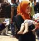 Una mujer lleva en brazos a su hijo en su huida de Mosul