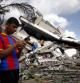 Un menor palestino con una camiseta del Barça mira su móvil en Gaza, donde los bombardeos israelíes han destruido diversos inmuebles
