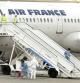 El avion de Air France en pista y personal sanitario con trajes de protección