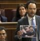 El portavoz socialista, Antonio Hernando (d), muestra unas fotografías durante su intervención en la sesión de control que celebra el Congreso, la primera a la que se somete el presidente del Gobierno, Mariano Rajoy, desde el estallido del caso del exvicepresidente Rodrigo Rato.