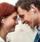 Close up of happy couple of teenagers listening to music using the same pair of earphones, looking at each other with love. Technology, romance concept. Side view. Web Banner (Close up of happy couple of teenagers listening to music using the same pai