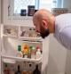 A young adult looks into his fridge.