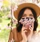 Woman wearing face mask decorated with flowers. Stylish handmade cotton mask. Spring blossom garden
