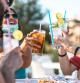Jóvenes disfrutan de unos cócteles en la terraza de un bar durante el verano.