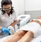 Personal sanitario realizando el tratamiento de depilación laser en las piernas a una mujer