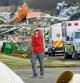 A woman walks away from a row of ambulances on the property of Mayfield Consumer Products Candle Factory after it was destroyed by a tornado, in Mayfield, Kentucky, on December 11, 2021. - Tornadoes ripped through five US states overnight, leaving more than 70 people dead Saturday in Kentucky and causing multiple fatalities at an Amazon warehouse in Illinois that suffered 