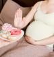 Close up of pregnant woman staying in bed rejects to eat junk food such as donuts and makes no gesture. Healthy diet for future mother concept.