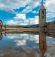 People stand in front of the ruins of the church of Sant Roma de Sau, at the swamp of Sau, located in the province of Girona in Catalonia on August 23, 2022. - The swamp of Sau is a reservoir on the Ter river, created by a dam located in the municipality of Vilanova de Sau. The marsh, built from 1947 to 1962, covered the village of Sant Roma de Sau which is still visible, including the bell tower of the 11th century Romanesque church, when the reservoir water level is low. The church of the Sau swamp is registered as the world's oldest that is preserved upright in water. (Photo by Josep LAGO / AFP)