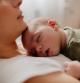 Photo of a young mother holding her newborn baby, while putting him to sleep