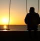 Man alone on a swing looking at empty seat