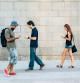 A small group of people playing a game on their smart phones and walking around the city.