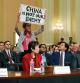 WASHINGTON, DC - FEBRUARY 28: A protester disrupts the first hearing of the U.S. House Select Committee on Strategic Competition between the United States and the Chinese Communist Party as (L-R) Scott Paul, president of the Alliance for American Manufacturing, human rights activist Tong Yi, and Lt. Gen. H.R. McCaster (Ret.) testify, at the Cannon House Office Building on February 28, 2023 in Washington, DC. The committee is investigating economic, technological and security competition between the U.S. and China. Kevin Dietsch/Getty Images/AFP (Photo by Kevin Dietsch / GETTY IMAGES NORTH AMERICA / Getty Images via AFP)