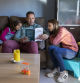 LECTURA EN FAMILIA. UN PADRE LEE UN LIBRO A SUS DOS HIJAS EN EL COMEDOR DE SU CASA
