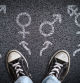 A person standing on asphalt road with gender symbols of male, female, bigender and transgender.  Concept of choice or gender confusion or dysphoria. (A person standing on asphalt road with gender symbols of male, female, bigender and transgender.  Co