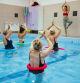 Female instructor is showing exercise to a group of active senior women during aqua aerobic class.