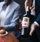Close up shot of a Sommelier showing red wine bottle to business guests at the restaurant table