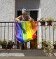 Una mujer cuelga la bandera arcoiris de su balcón