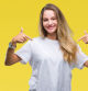 Young beautiful blonde woman wearing casual white t-shirt over isolated background looking confident with smile on face, pointing oneself with fingers proud and happy.