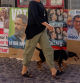 FILE PHOTO: A woman with her dog walks past electoral posters of Spain's left-wing Sumar leader Yolanda Diaz, Spain's far-right Vox party leader Santiago Abascal, Spain's acting Prime Minister and Socialist leader Pedro Sanchez and Spanish opposition People's Party leader Alberto Nunez Feijoo, ahead of the July 23 snap election, in Ronda, Spain July 7, 2023. REUTERS/Jon Nazca/File Photo