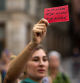 A demonstrator holds a red card reading in Spanish 