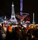 People walk in front of an illuminated Eiffel tower at a Christmas fair installed inside the Jardin des Tuileries in Paris, France, December 18, 2023. REUTERS/Sarah Meyssonnier