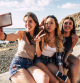 Millennial girls taking selfie picture with modern phone for social media having lot of fun together in friendship - smile and crazy expression people outdoor at the beach for summer holiday