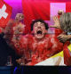 12 May 2024, Sweden, Malmo: Nemo (C) from Switzerland reacts during the scoring at the final of the Eurovision Song Contest (ESC) 2024 in the Malmo Arena. Photo: Jens Büttner/dpa
