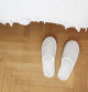 White slippers on a wooden floor in bedroom.