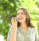 Happy woman recording audio message on phone in a park