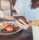 Young woman using smart phone and enjoy eating dessert in cafe on vacation trip