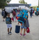 Padres que cargan con las mochilas de sus hijos, que parten de colonias en Cornellà