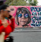 A woman walks past a mural created by Maca_dessine depicting Gisele Pelicot in Gentilly, south of Paris on September 21, 2024 as her former partner Dominique Pelicot is accused of drugging her for nearly ten years and inviting strangers to rape her at their home in Mazan. A court in the southern town of Avignon is trying Dominique Pelicot, a 71-year-old retiree, for repeatedly raping and enlisting dozens of strangers to rape his heavily sedated wife in her own bed over a decade. Fifty other men, aged between 26 and 74, are also on trial for alleged involvement, in a case that has horrified France. The court proceedings, which runs until December, are open to the public at the request of Dominique Pelicot's ex-wife and victim. (Photo by GEOFFROY VAN DER HASSELT / AFP) / RESTRICTED TO EDITORIAL USE - MANDATORY MENTION OF THE ARTIST UPON PUBLICATION - TO ILLUSTRATE THE EVENT AS SPECIFIED IN THE CAPTION