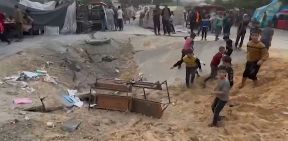 Los niños juegan en un cráter como si fuera un tobogán tras un ataque a una escuela en Gaza